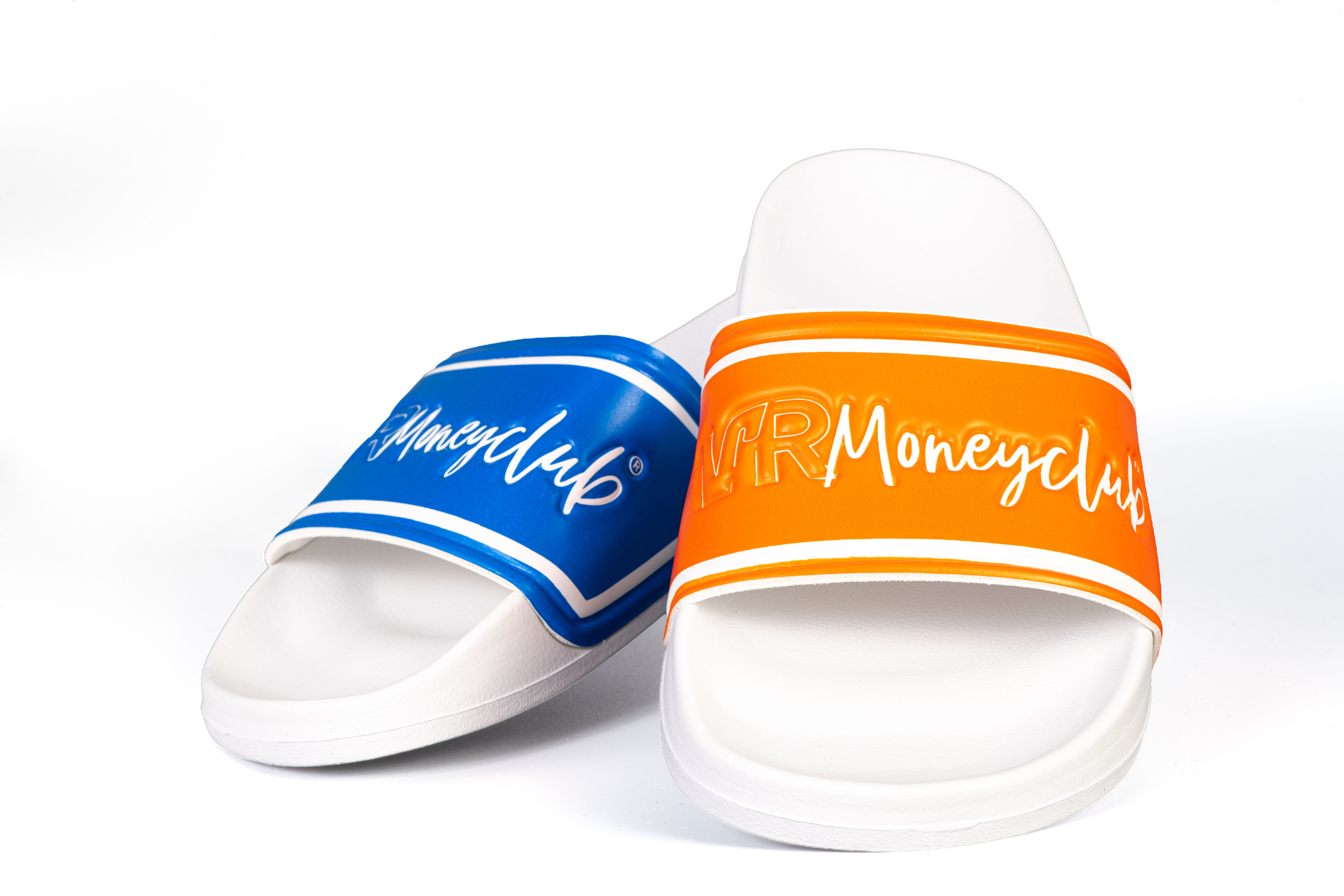 Ein Paar weiße YOBA Badeschlappen im Mismatch-Design; der linke Schuh hat einen blauen Riemen, der rechte einen orangefarbenen Riemen, beide mit dem weißen Relief-Schriftzug „VR Moneyclub“ versehen, freigestellt auf weißem Hintergrund.